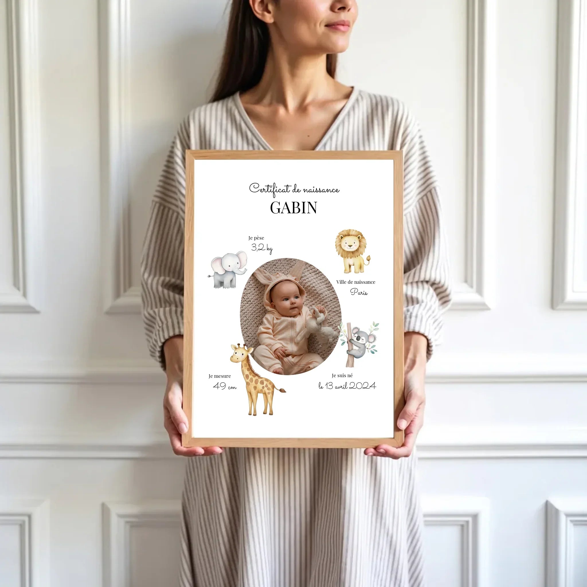 Femme tenant un cadre personnalisé certificat de naissance bébé avec animaux mignons illustrés.