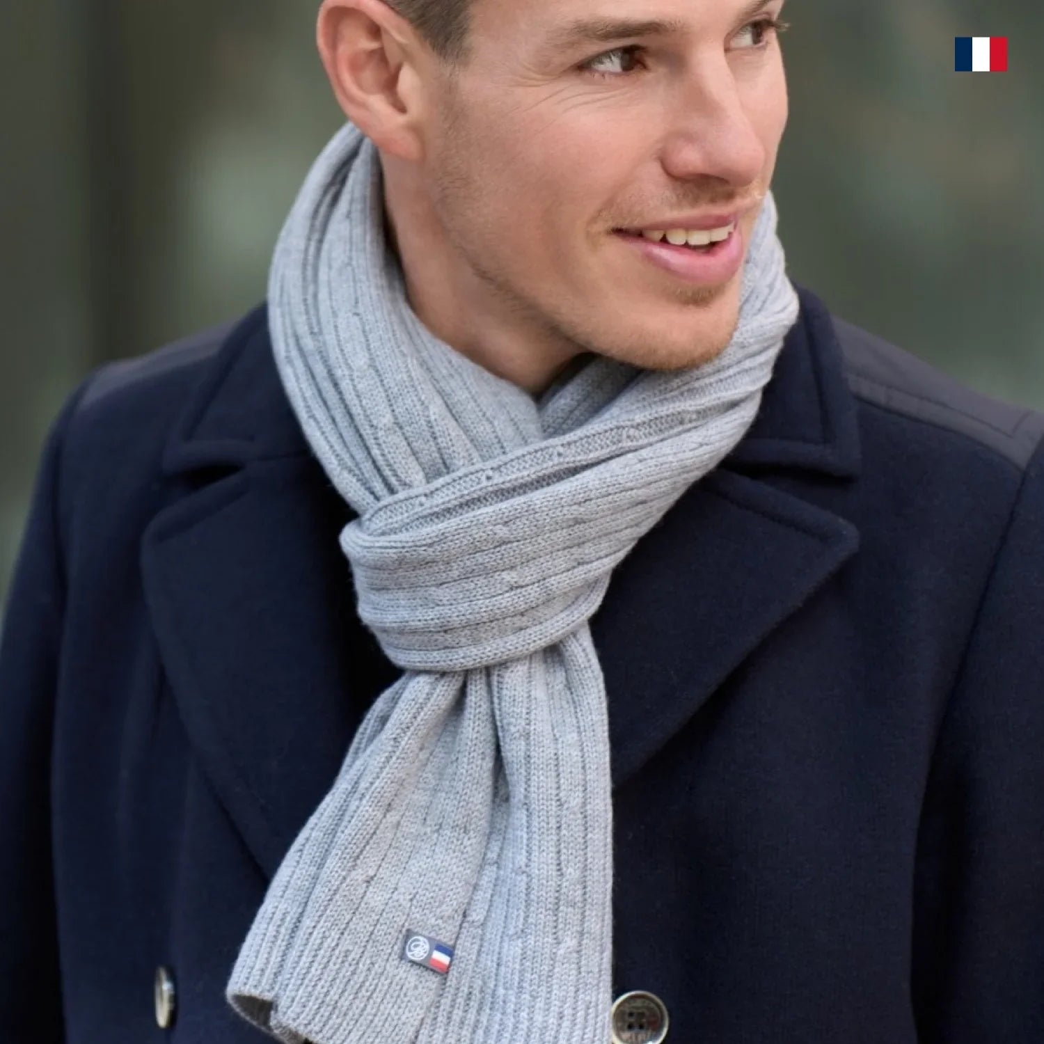 Homme portant une écharpe grise en laine made in France, manteau bleu, style élégant
