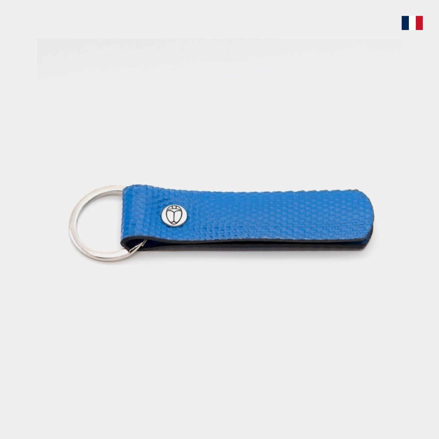 Porte-clés cuir bleu avec anneau métallique, texture grainée, fond clair, fabriqué en France.