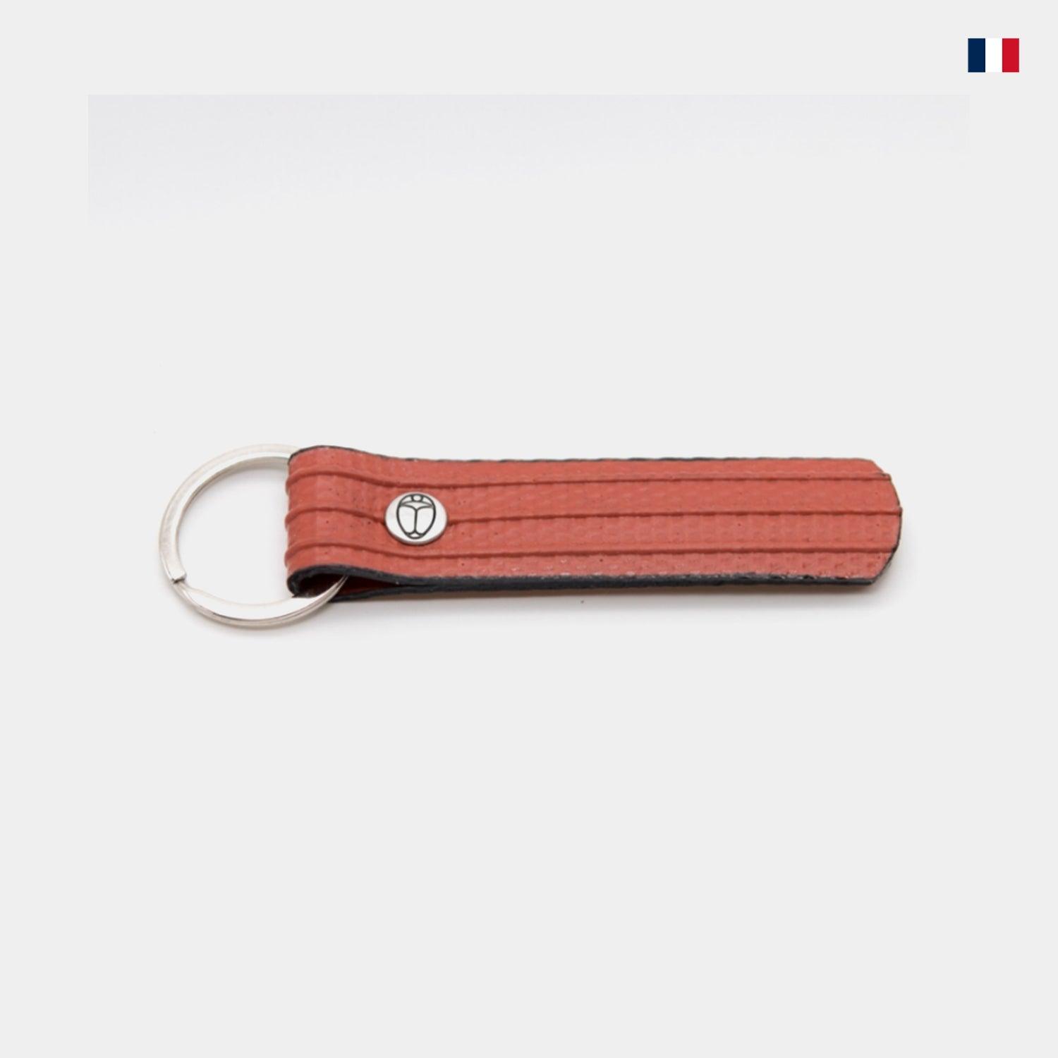 Porte-clés orange en cuir recyclé avec anneau en métal, design sobre, fond blanc.