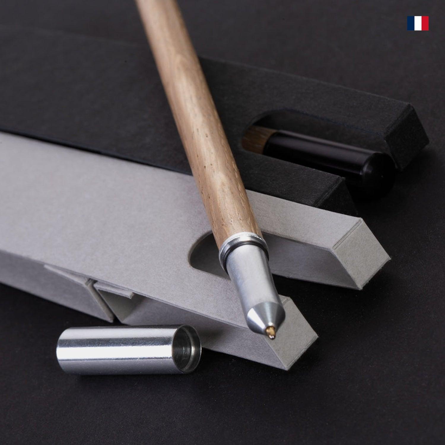 Stylo en bois de chêne avec capuchon métal, posé sur un coffret élégant, fond noir.