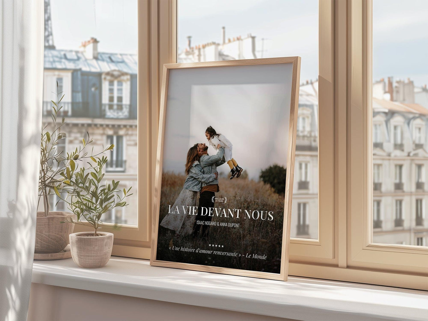 Affiche personnalisée posée sur un rebord de fenêtre, décor intérieur, plantes en pot, vue sur immeubles parisiens.