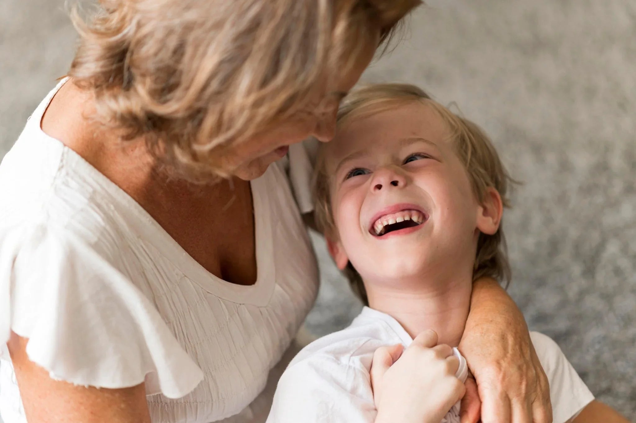 Grand-mère souriante serre son petit-fils dans ses bras, moment de tendresse et joie famille