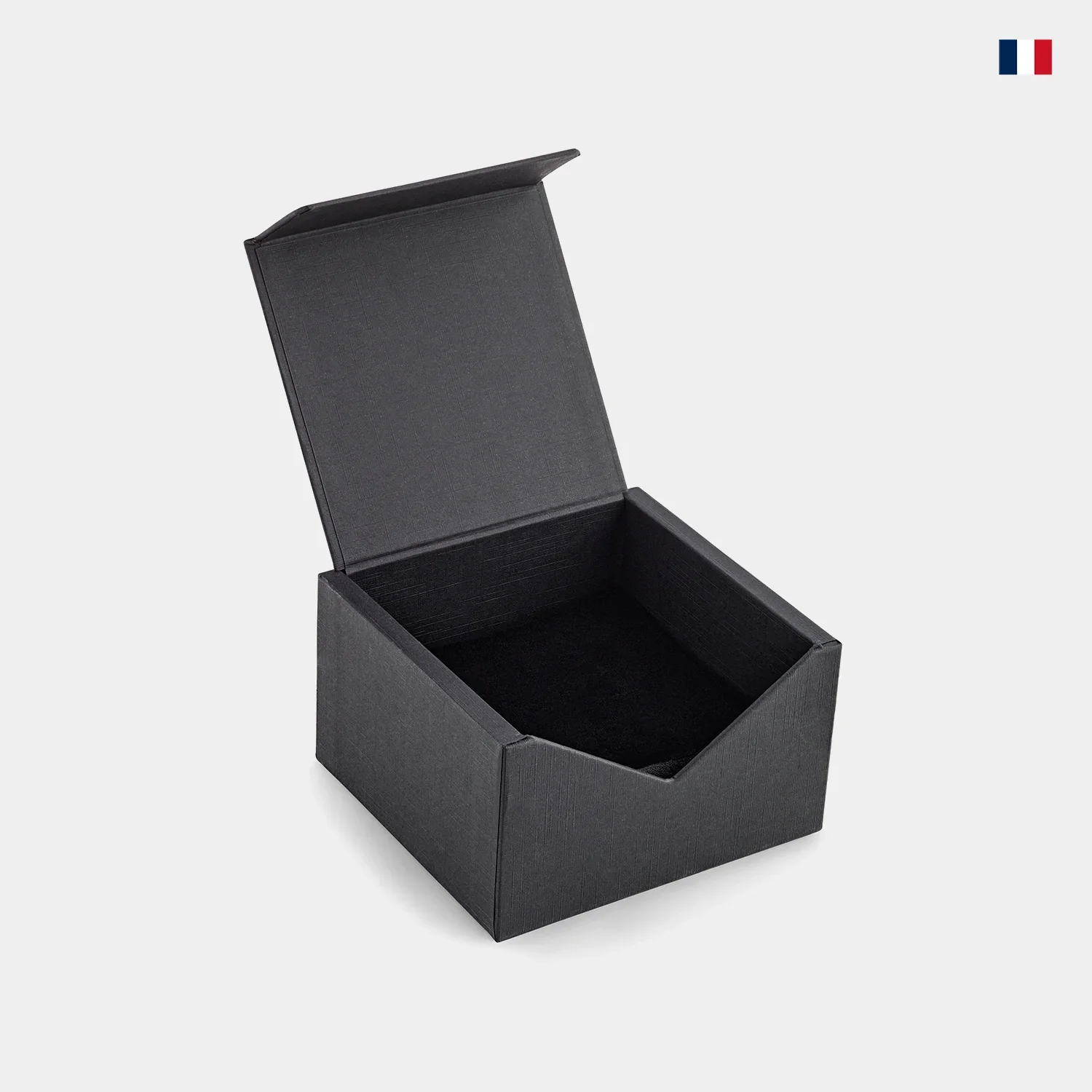 Boîte cadeau noire ouverte, fond clair, angle droit, drapeau français en haut à droite.